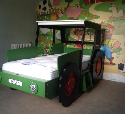 dark green tractor with red wheels in front of farm mural